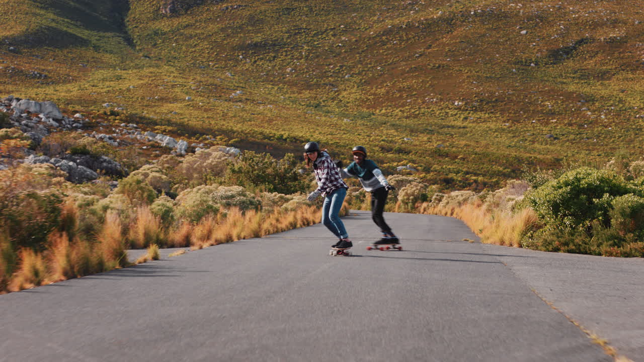 jóvenes amigos haciendo longboard juntos navegando por el campo carreras de carretera divirtiéndose montando en patineta usando casco protector adolescentes felices vacaciones de verano