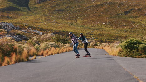 young friends longboarding together cruising on countryside road racing having fun riding skateboard wearing protective helmet happy teenagers summer vacation