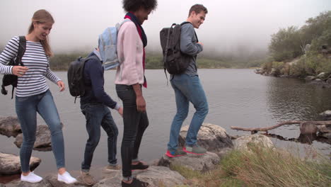 four friends on a walk taking a break by the edge of a lake