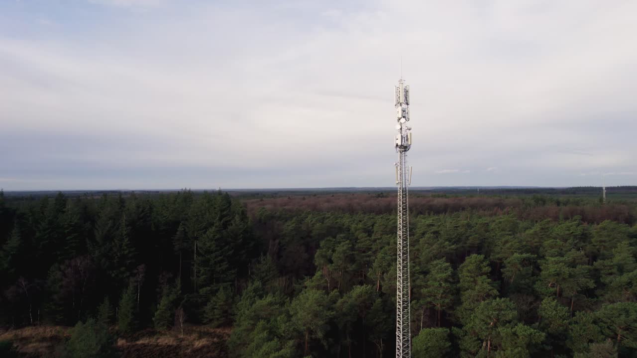 Paesaggio aereo con antenna tecnica di comunicazione e trasmissione dati bianca a contrasto nel parco naturale di Veluwe, con stazione di servizio lungo l'autostrada A1 nei Paesi Bassi