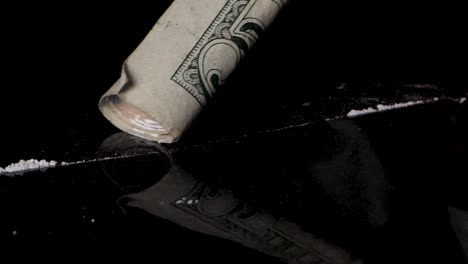 snorting cocaine line with a rolled banknote, isolated on black reflective background