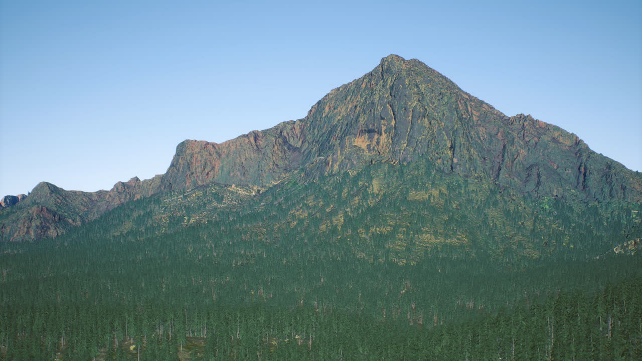 Majestic mountain peak rises above dense evergreen forest in clear sky