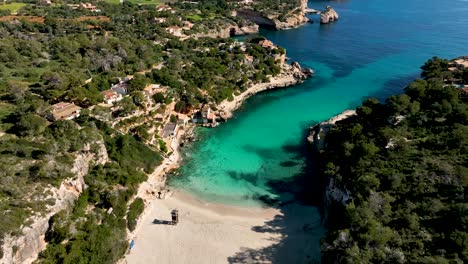 drone flying backwards revealing beach of cala llombards and es pontas on mallorca, spain