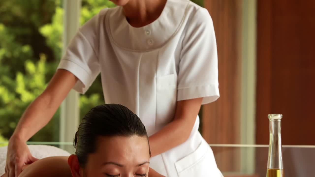 매력적인 갈색 여성이 마사지를 받고 있습니다.