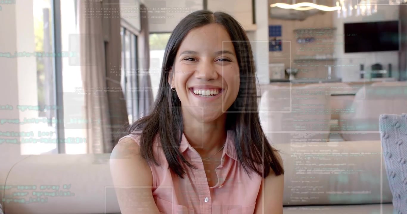 Su un divano grigio, una donna inizia a sorridere e poi scoppia a ridere, mentre sovrapposizioni di codice mostrano tecnologia digitale.