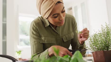 video of happy biracial woman in hijab smelling herbs