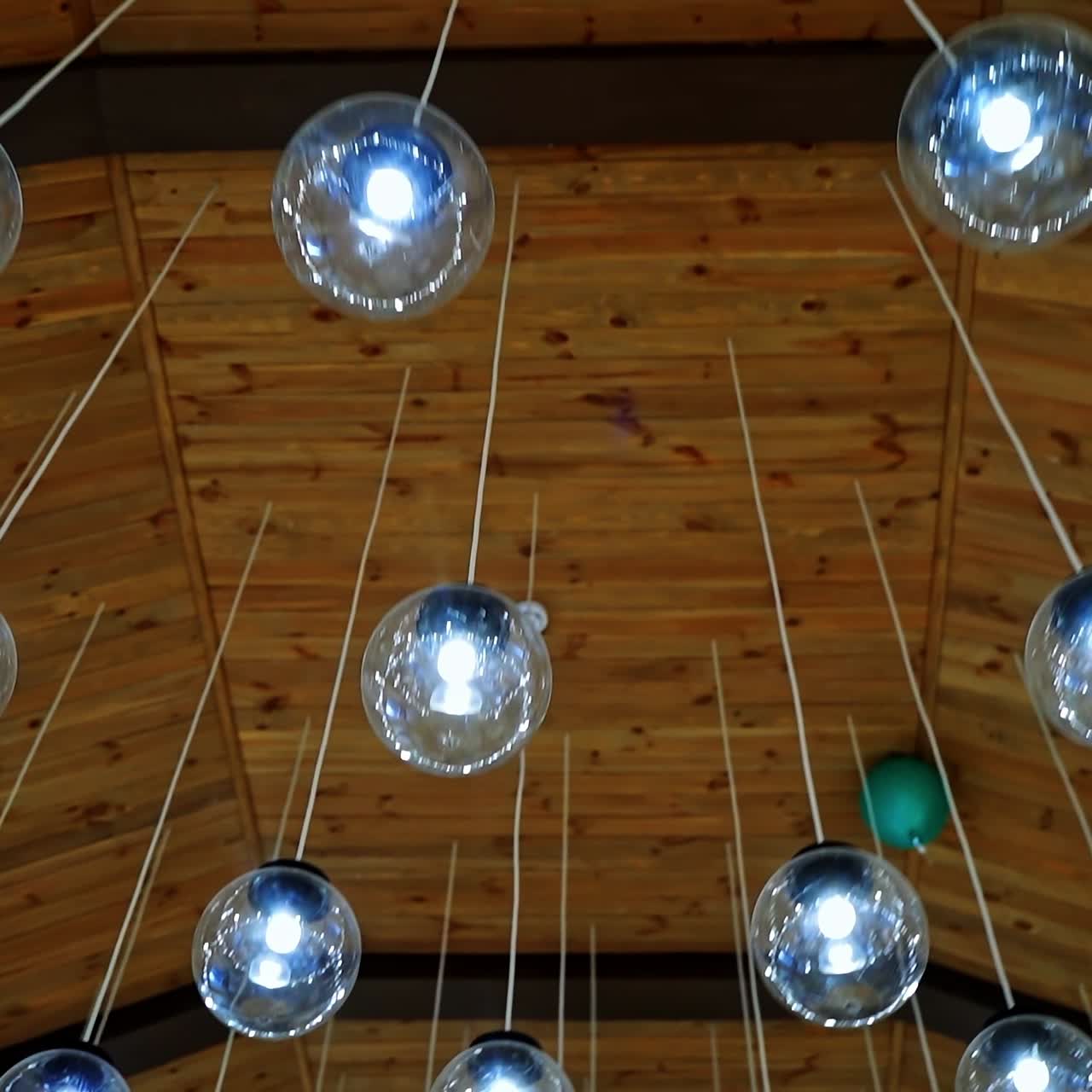 Cozy ceiling with many crystal small balls. Round light bulbs hanging on white wires. Modern design of shiny light lamps.