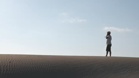 man calling with a smart phone in the desert dunes alone. copy space