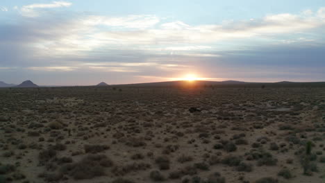 four-wheel drive vehicle driving along a dirt trail during a romantic sunset in the mojave desert - aerial view