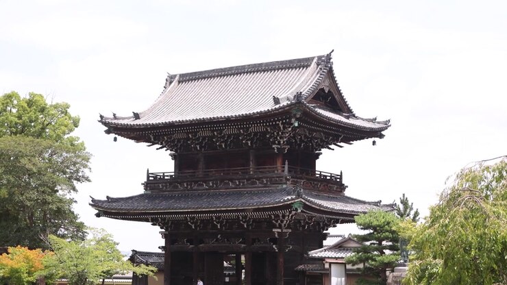 Udsigt til en traditionel buddhistisk tempelport i træ i Arashiyama, Kyoto, Japan, omgivet af grønne områder og med klassisk japansk religiøs arkitektur