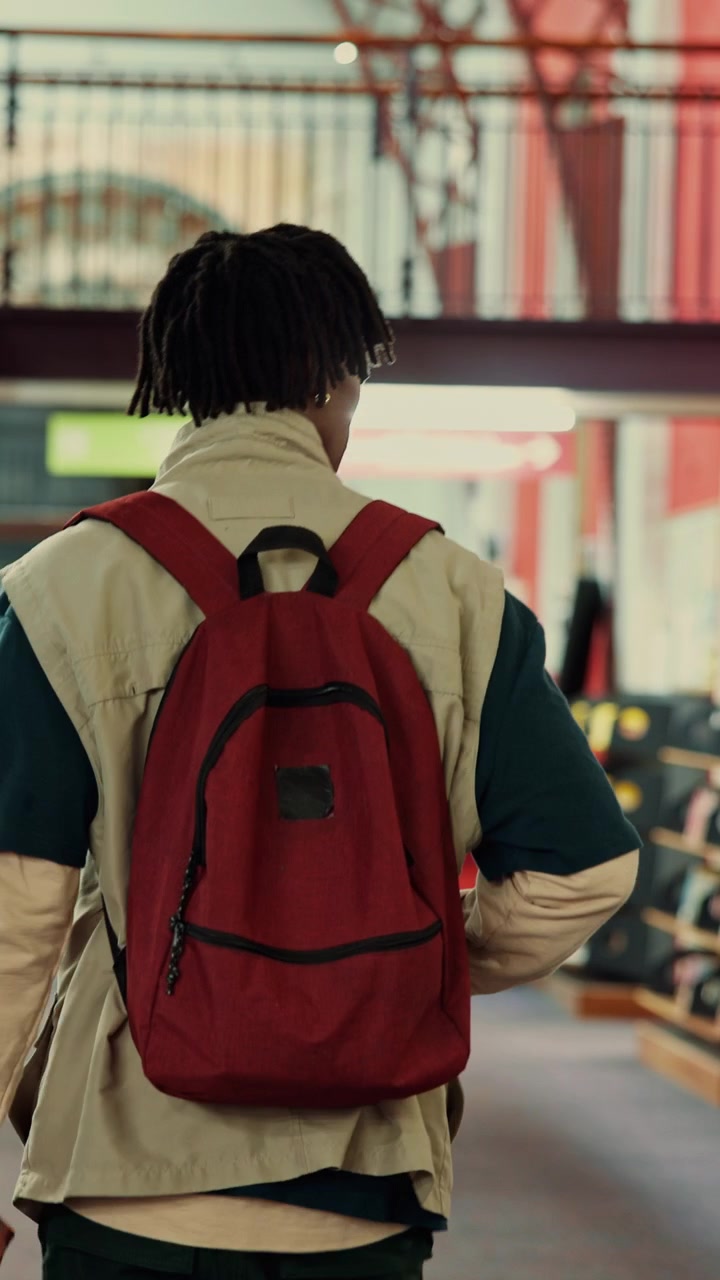 Young Man With Red Backpack Walking Through Indoor Public Space