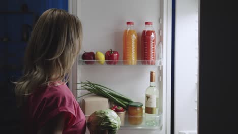 woman looking in fridge at night