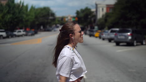 mujer joven cruzando casualmente la calle de un pequeño pueblo - vista de retrato