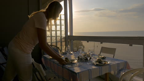 mujer sirviendo cena en el balcón de la casa