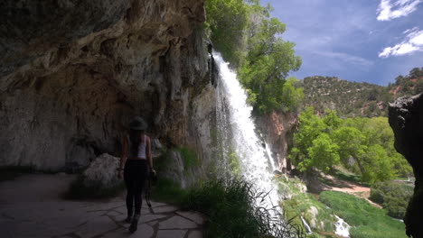 mujer joven caminando en una cueva bajo majestuosas cascadas