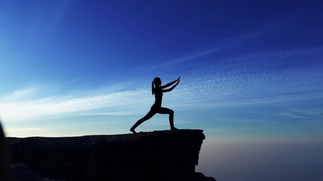 Serene Silhouette of a Person Practicing Yoga on a Cliff at Dusk