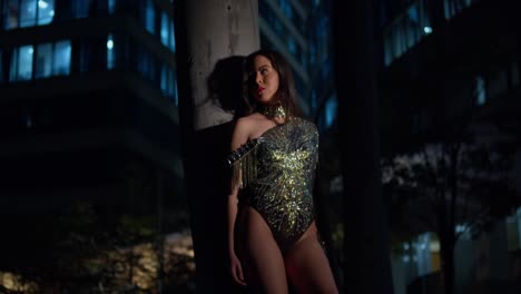 jovencita con un vestido reluciente a la derecha con luces de la ciudad por la noche en el fondo