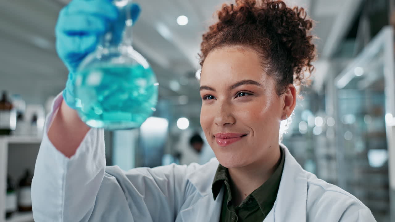 A scientist examines a flask in her laboratory