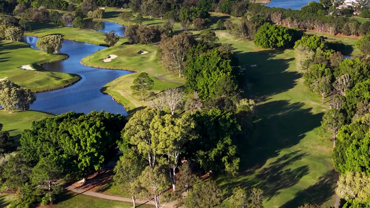 Ripresa aerea con drone rivela un paesaggio scenografico di campo da golf con ostacoli d'acqua e alberi fitti