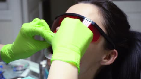 vista en primer plano de las manos del dentista poniendo una presa de goma en la boca de una paciente femenina. filmado en 4k