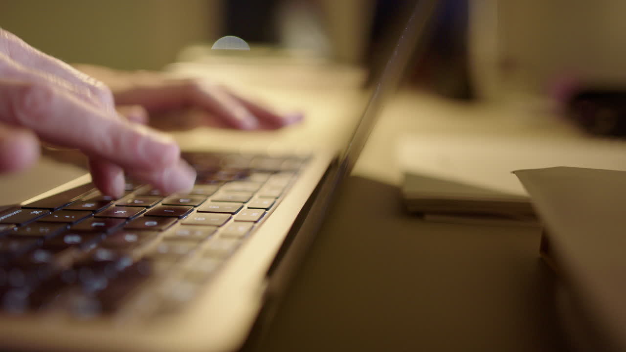 Online scammer typing fast on laptop keyboard, side view shallow focus pan