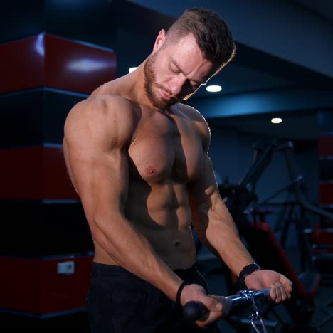 handsome fitness trainer doing workout for hands in gym. modern equipment for sport. slow motion