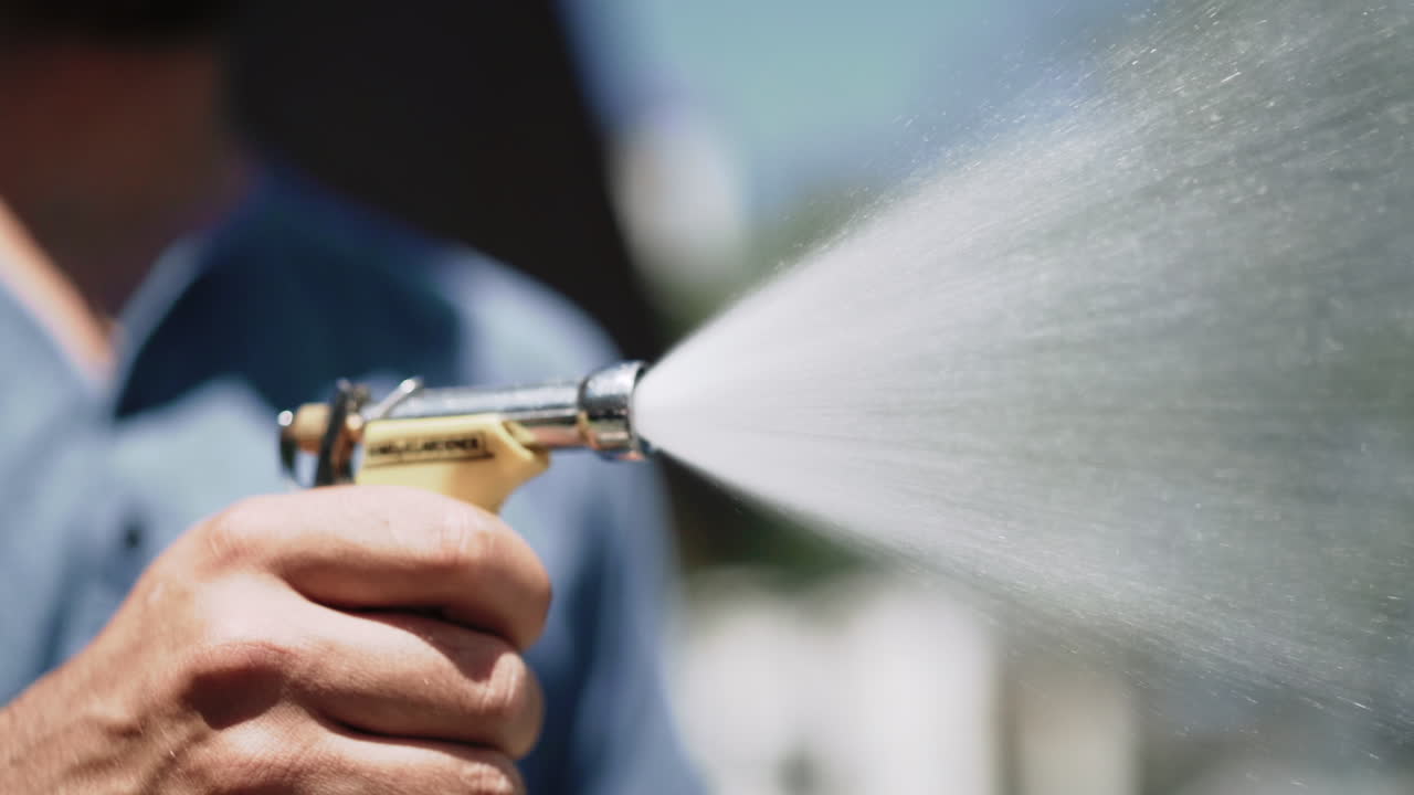 A person spraying a hose on a sunny summer day in Canada