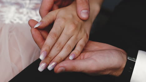 groom in suit holds hand of future wife sitting together