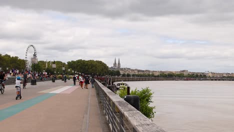 crowds walk and cycle along the riverbank