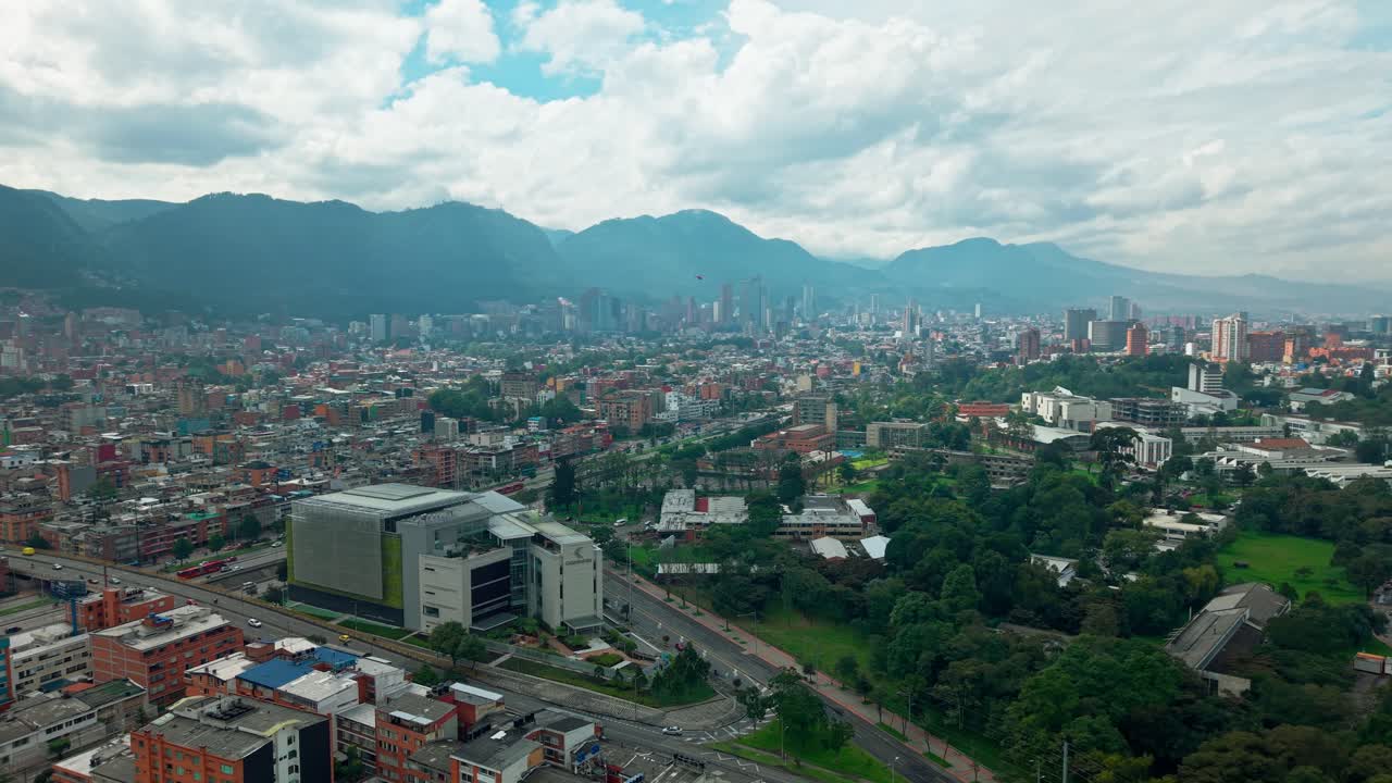 Panoramic aerial view of Bogota, Colombia on a cloudy day with contrasting low-rise architecture and skyscrapers, helicopter flying over the city.