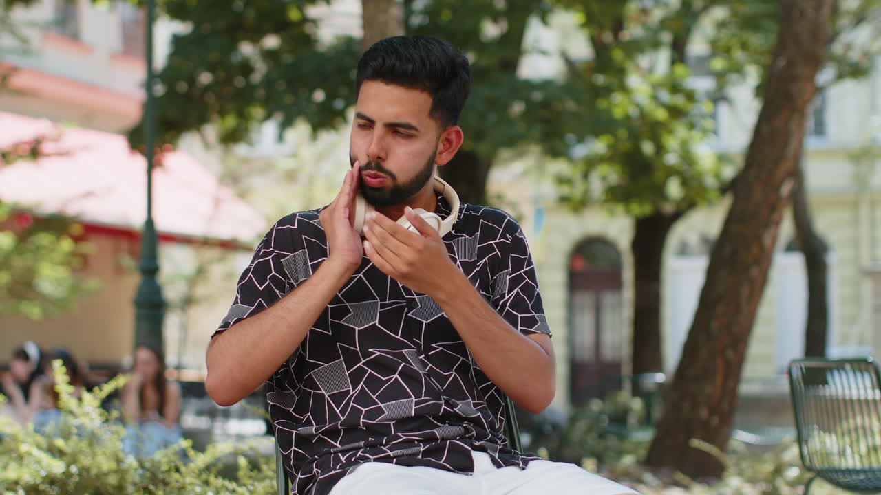 Frustrated sick ill indian man touching cheek suffer from painful toothache sensitive teeth cavities