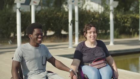 retrato de una feliz pareja de discapacitados en sillas de ruedas tomados de la mano