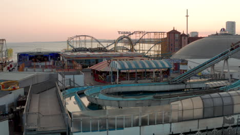 Aerial-slider-shot-along-closed-rides-on-Brighton-Pier-at-sunset