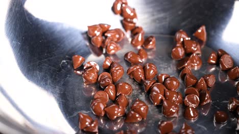 chocolate chips being poured into a metal bowl