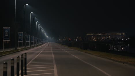 empty road under streetlights leads towards a glowing stadium at night in zagreb