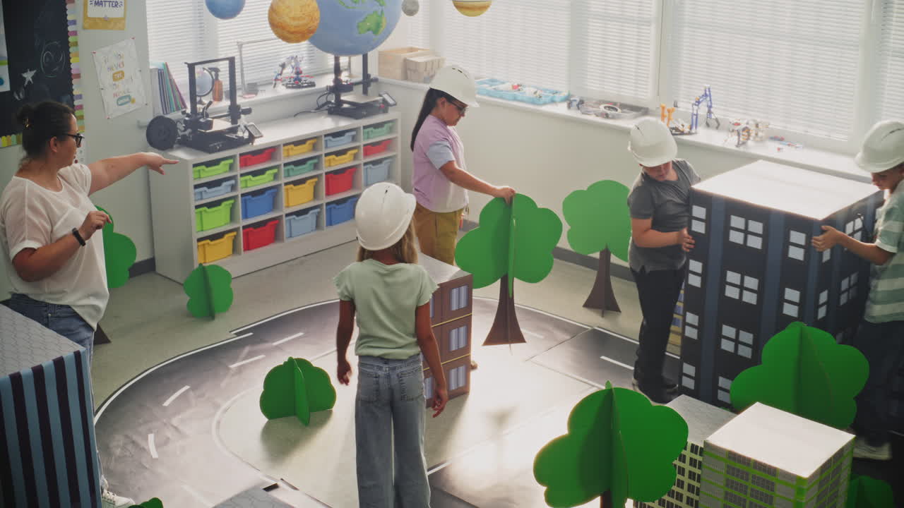 Female Teacher Guiding Elementary School Children in Classroom Activity with Cardboard Urban
