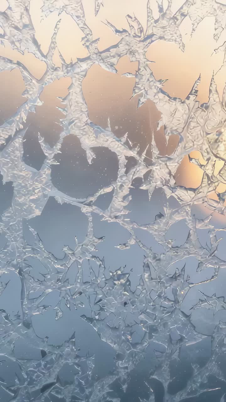 Video verticale: inquadratura di una finestra ghiacciata in casa, la fotocamera scorre mentre l'alba riscalda i motivi del gelo