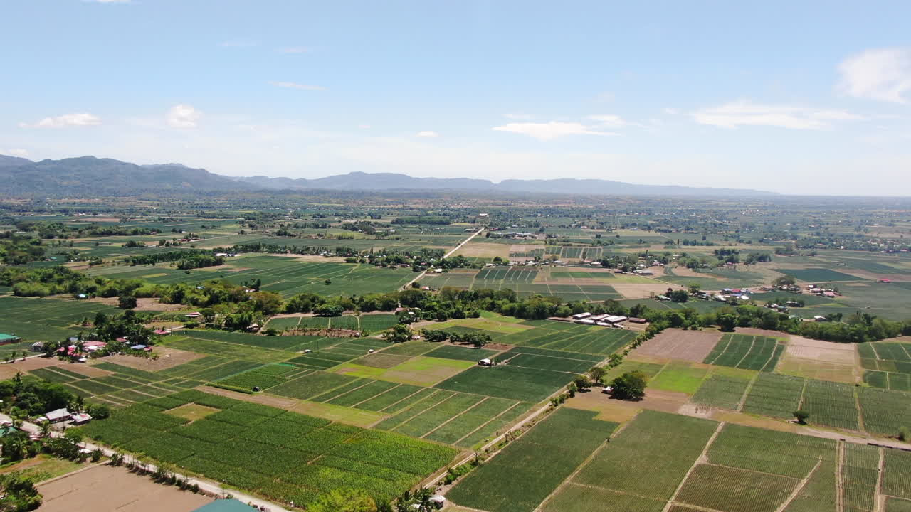vista aérea de un amplio campo verde con casas, árboles y montañas con un cielo azul claro durante el día en calidad 4k
