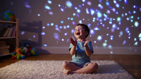 excited toddler clapping while watching colorful light reflections