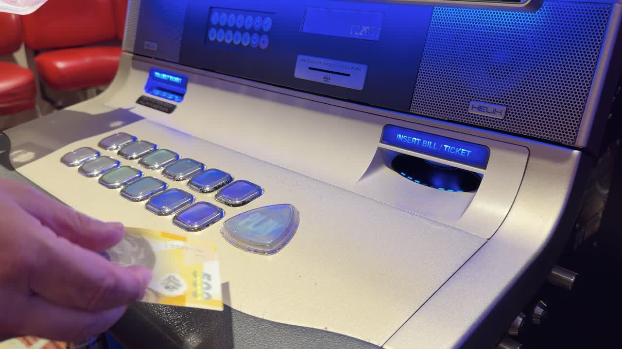A person inserts Philippine Peso banknotes into a modern slot machine at a casino