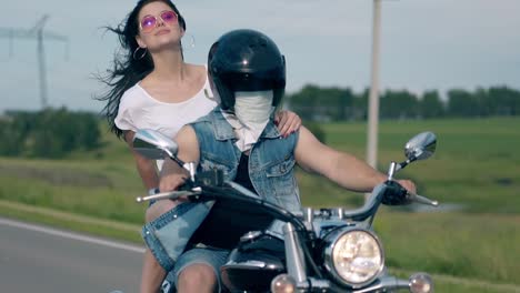 brunette lady in white t-shirt rides motorbike with man