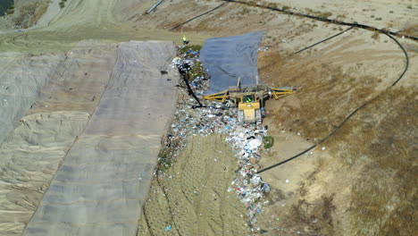 aerial view of a landfill with heavy machinery pushing waste