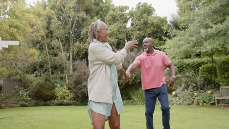 Happy-senior-african-american-couple-holding-hands-and-walking-in-garden,-slow-motion