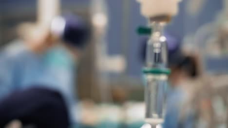 goteo intravenoso y cirujanos ocupados en el fondo