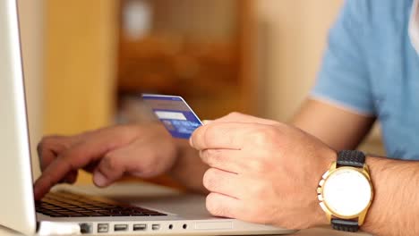 primer plano de un hombre comprando en línea usando una computadora portátil con tarjeta de crédito 1