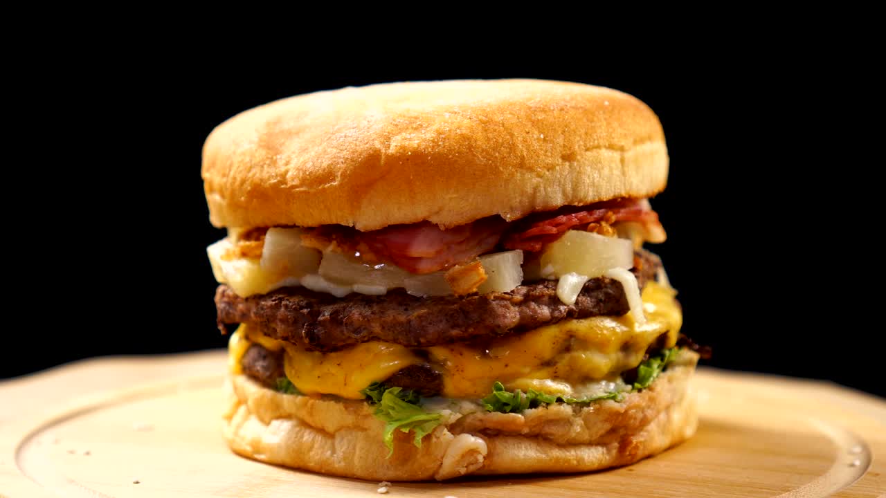 Fresh appetizing hamburger fast rotating on black background. Seamless loopable shot.