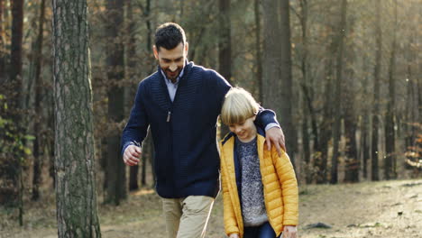 Padre-Feliz-Caucásico-Y-Su-Pequeño-Hijo-Caminando-Y-Hablando-En-El-Bosque