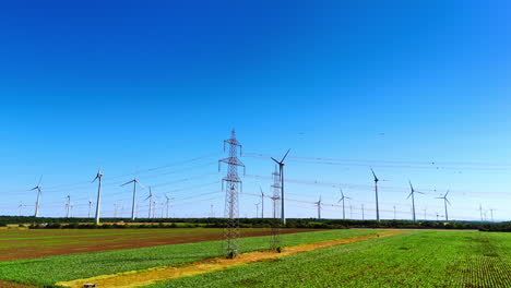 vast fields in the country with electricity lines and wind turbines. amazing clear blue sky at backdrop