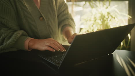 Hände-Auf-Der-Laptop-Tastatur.-Silhouette-Vor-Dem-Hintergrund-Eines-Fensters,-Aus-Dem-Die-Untergehende-Sonne-Scheint