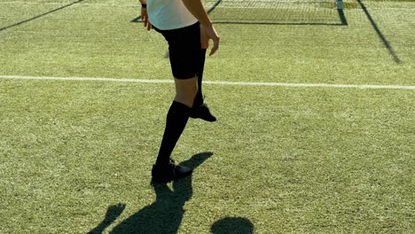 a young soccer man training freestyle tricks with the ball on a street football pitch on a sunny day 1